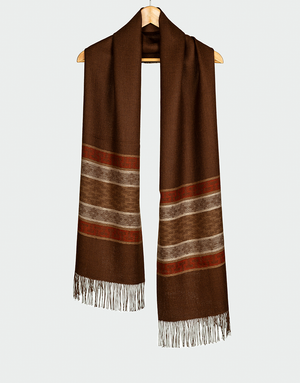 Bufanda marrón con franjas horizontales en beige rojo y gris textura suave con flecos colgada en gancho de madera estilo rústico elegante