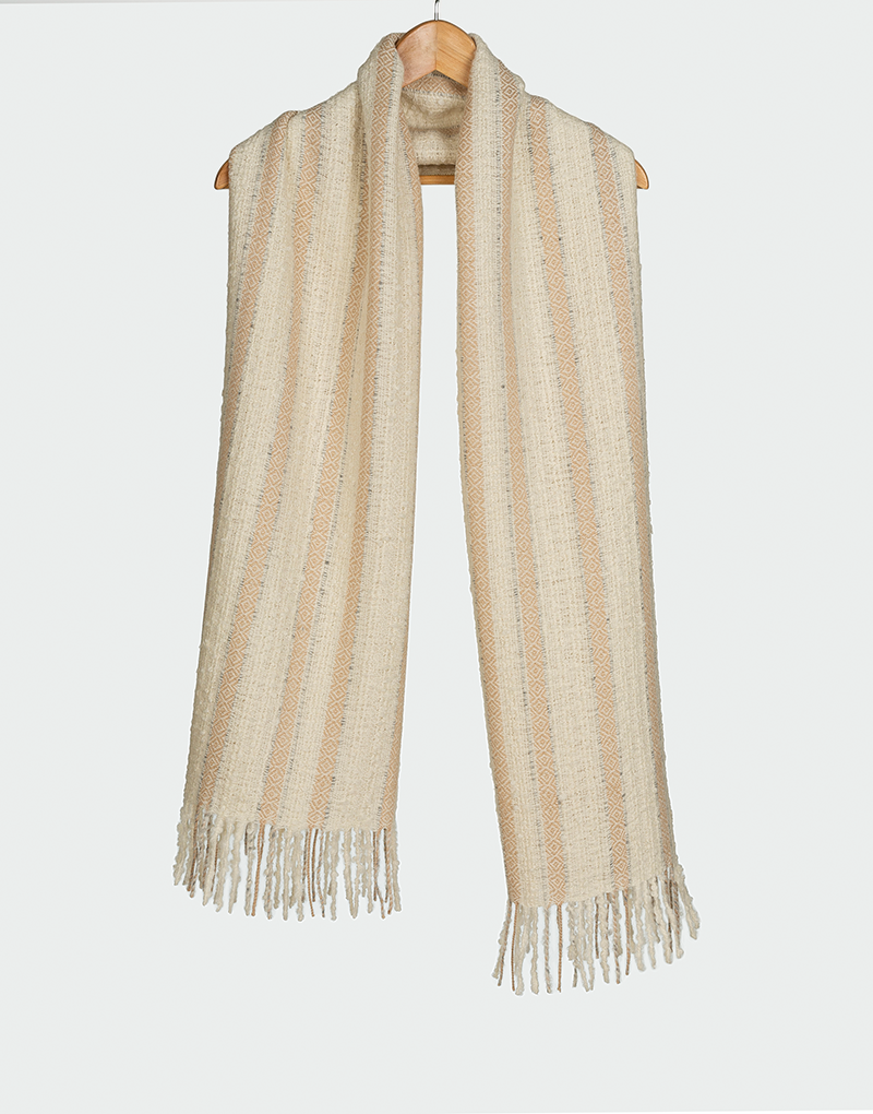 Bufanda beige claro con franjas verticales en tonos arena y crema con flecos cortos colgada en gancho de madera