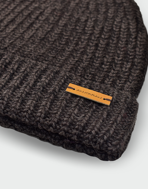Gorro tejido de lana baby alpaca en color marrón oscuro con textura acanalada y etiqueta de cuero con logo de ANNTARAH