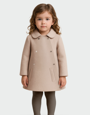 Niña con abrigo beige de lana baby alpaca, diseño clásico de doble botonadura y bolsillos frontales, ideal para moda infantil elegante y sostenible