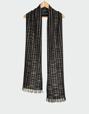 Bufanda tejida en patrón de rayas verticales en negro gris y marrón con textura ligera y flecos finos colgada en gancho de madera