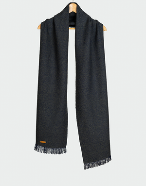 Chalina azul marino con diseño de espiguilla en contraste sutil y terminación en flecos cortos estilo clásico colgada en gancho de madera