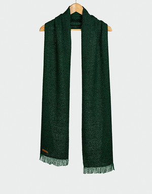 Chalina verde oscuro con patrón de espiguilla y flecos cortos colgada en gancho de madera diseño elegante y texturizado